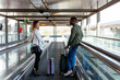 © David Prado/Stocksy - young multiracial couple on the walkway at the airport with luggage