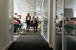 © David Prado/Stocksy - Business partners communicating in hall of office