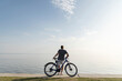 © Westend61 - Man standing with bicycle looking at sea against blue sky