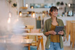 © KNSY/Westend61 - Smiling female entrepreneur looking away while holding digital tablet standing in cafe