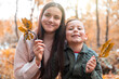 © William Perugini/Westend61 - Brother and sister holding dry leaves while standing in Cannock Chase park during autumn