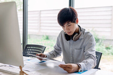 Wall Mural - young asian man working design and develop mobile application software on digital tablet.