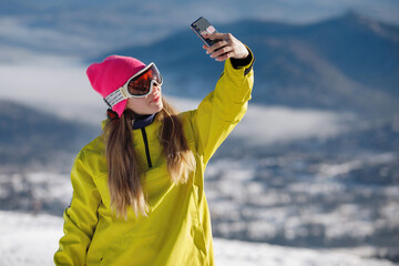 Woman makes selfie in winter mountains landscape.