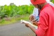 © PRASANNAPIX - Young indian farmer sign on document with banker at agriculture field