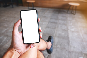 Mockup image of a hand holding and showing mobile phone with blank white screen in cafe