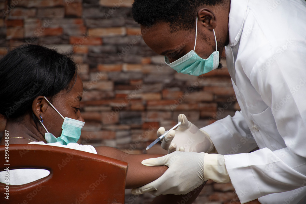 african doctor injecting an african woman with a vaccine for covid 19 - obrazy, fototapety, plakaty 