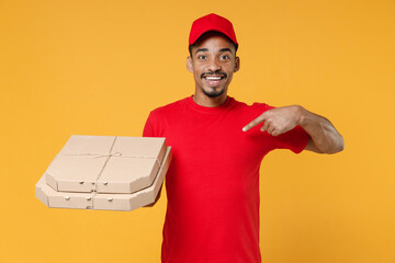 Wall Mural - Delivery employee african man 20s in red cap blank print t-shirt uniform workwear work courier dealer service concept hold give food order pizza cardboard boxes isolated on yellow background studio.