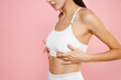 © ViDi Studio - Cropped image side view beautiful young brunette woman 20s in white brassiere underwear put hand on chest breast cancer early diagnostic therapy treatment isolated on pink background, studio portrait.