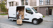 © VAKSMANV - Caucasian handsome young delivery man post office worker delivering home many boxes. Ordered shipment. Male courier employee in uniform brings parcels to client house. Supply concept