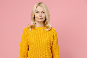 Wall Mural - Smiling charming beautiful elderly gray-haired blonde woman lady 40s 50s years old wearing yellow casual sweater standing and looking camera isolated on pastel pink color background studio portrait.