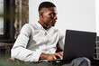 © Drobot Dean - Afro american young man sitting in armchair and working with laptop