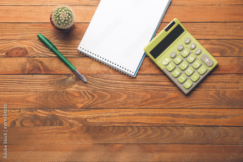 Modern calculator and stationery on wooden background