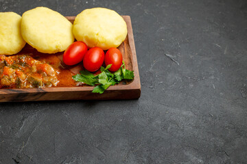 Horizontal view of dinner preparation with uncooked vegetables on a brown cutting board