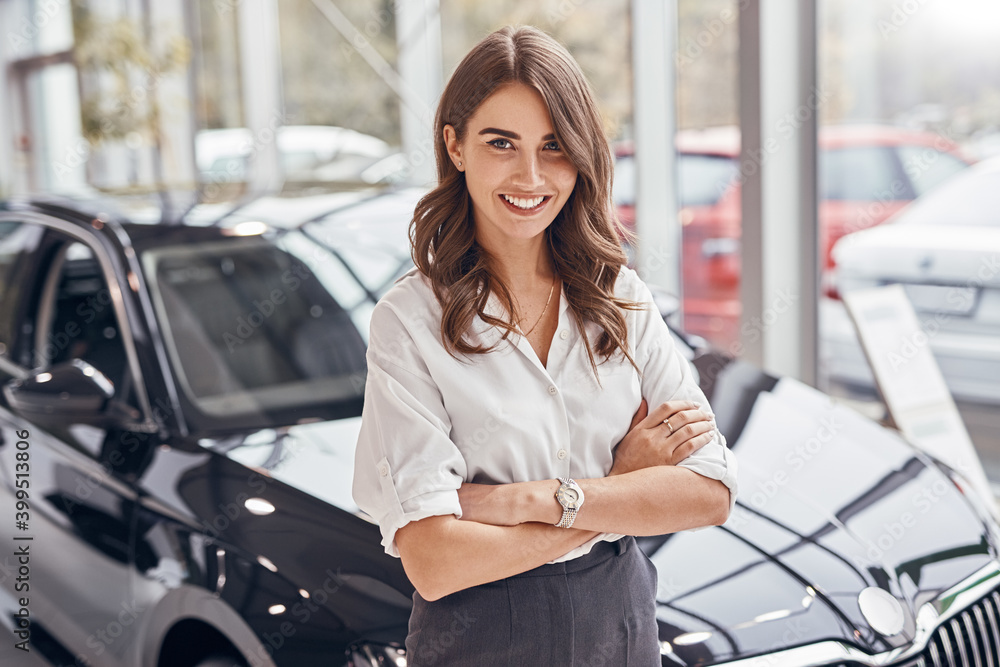 Confident female dealer standing near car - obrazy, fototapety, plakaty 