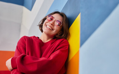 happy female hipster leaning on colorful wall