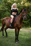 Fototapeta Konie - Beautiful woman stands with a horse in nature on the background of the forest