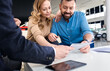 © Zoran Zeremski - Mid-adult couple talking with sales agent and signing contract for new car in modern car showroom.