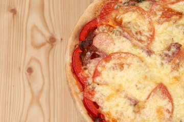 Tasty, hot pizza with tomato on a wooden board. Homemade food. Top view with copy space.