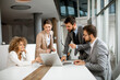 © BGStock72 - Group of young business people working and communicating while sitting at the office desk together