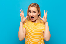 Young Blonde Woman Screaming With Hands Up In The Air, Feeling Furious, Frustrated, Stressed And Upset