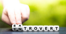Hand turns dice and changes the word introvert to extrovert.