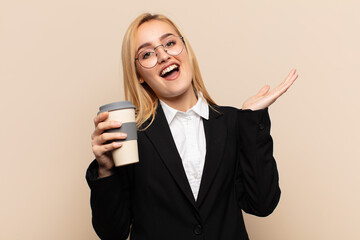 Wall Mural - young blonde woman feeling happy, amazed, lucky and surprised, celebrating victory with both hands up in the air