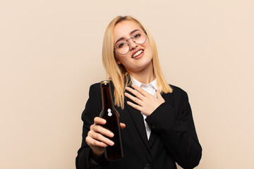 Wall Mural - young blonde woman feeling happy and in love, smiling with one hand next to heart and the other stretched up front