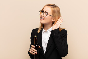 Wall Mural - young blonde woman looking serious and curious, listening, trying to hear a secret conversation or gossip, eavesdropping