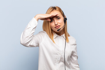 Wall Mural - young blonde woman looking bewildered and astonished, with hand over forehead looking far away, watching or searching