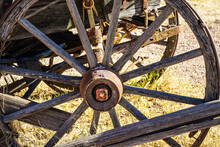 An Old Wagon Wheel Of Dried, Cracked Wood In Sunlight.