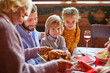 © Roman - contemporary large multi-generation family sitting by served festive table on Christmas day, have meal, having homemade food and drinks for dinner