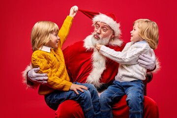 children torture Santa Claus to get gifts, have fun together, sitting on his knees, talking