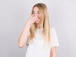 © Studio Nova - Young woman with disgust on his face pinches nose on white background. Negative emotion facial expression.