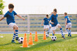 © matimix - Young footballer improving dribbling skills on turf football training pitch. Kids in sportswear play ball sports
