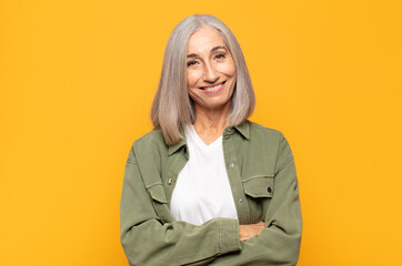 Wall Mural - middle age woman looking like a happy, proud and satisfied achiever smiling with arms crossed