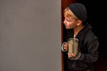 Wall Mural - lonely street boy begging, hiding behind builsing wall, poor and hungry boy in dirty wear