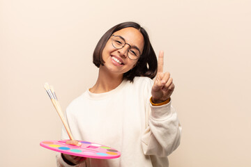 Canvas Print - young hispanic woman smiling and looking friendly, showing number one or first with hand forward, counting down