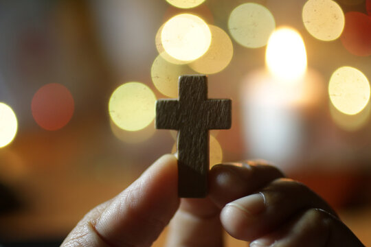 Wall Mural -  - Hand holding a cross. On blurry background of colorful bokeh lights. Love passion, faith and hope concept.