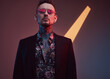 © Fxquadro - Handsome and tattooed guy dressed in black jacket with shirt weared with sunglasses poses in dark and colourful background.