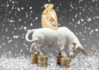 Miniature model of a bull with money coins and a bag of gifts. Bull as a symbol of 2021 reliability and stability. Idea for a Christmas card for Business, stock exchange, finance, investment.