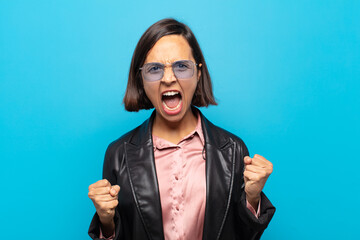 Sticker - young hispanic woman shouting aggressively with an angry expression or with fists clenched celebrating success