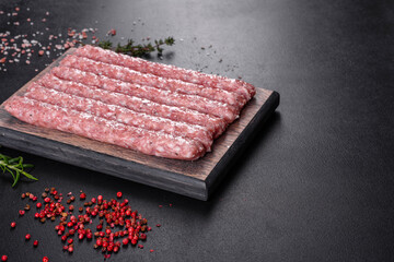 Fresh raw pork sausages with spices on a wooden cutting board