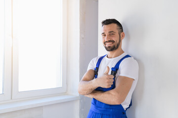 A craftsman in blue uniform stands against the wall and poses