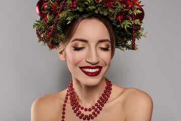 Poster - Beautiful young woman wearing Christmas wreath on grey background