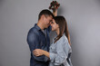 © New Africa - Happy couple standing under mistletoe wreath on grey background