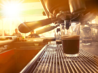 Glass cup with coffee in an espresso machine in a bar