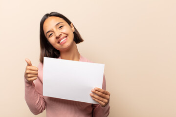 Canvas Print - young latin woman feeling proud, carefree, confident and happy, smiling positively with thumbs up