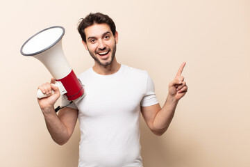 young handsome man looking excited and surprised pointing to the side and upwards to copy space