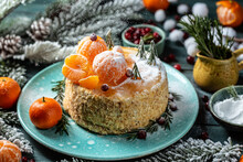 Homemade Christmas Tangerines Cake With White Cream, Fir Tree Branches On It Stands. Rosemary In The Form Of Christmas Trees. Atmospheric Photo