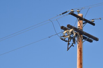 Power line with glass insulators and wires. One power pole off center, room for copy.  Blue sky in background.